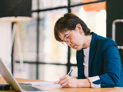 Business woman sitting at her desk in front of a laptop while during paperwork