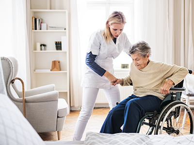 A nurse helping an older woman out of a wheel chair