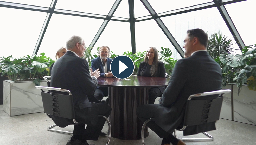 Five lawyers engaged in a discussion around a conference table.