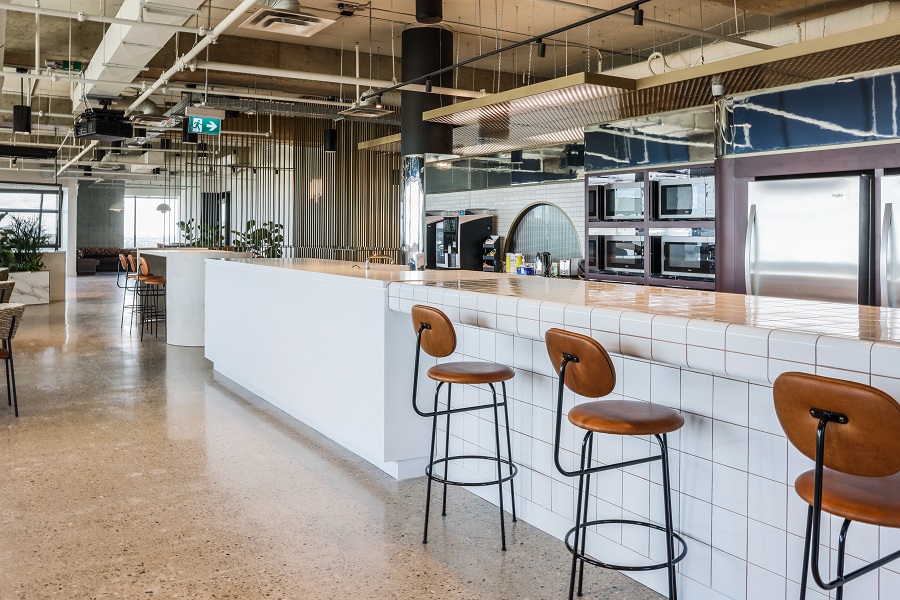 Long counter top with two bar stools and kitchenette in behind.