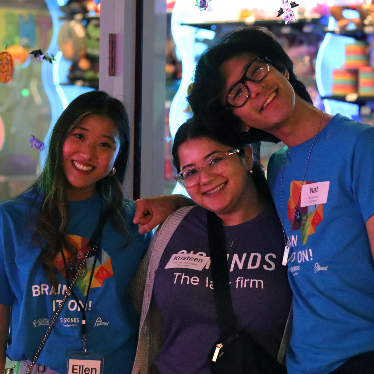 Articling students, Ellen Yoo, Kristeen Rodregus, and Nat Leung stand closely together smiling ahead. 