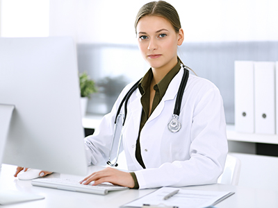 Female Doctor using a desktop computer looking into the camera
